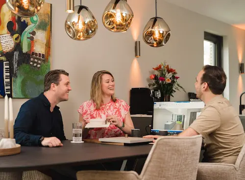 Stel zit aan tafel met een expert bij hun thuis.